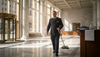 Concierge cleaning marble lobby with sunlight