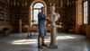 Sculptor dusting marble bust in luxury library