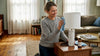 Woman dusting marble lamp in sunlit living room