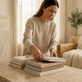 Woman arranging books on travertine table in marble-accented living room