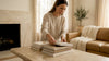 Woman arranging books on travertine table in marble-accented living room